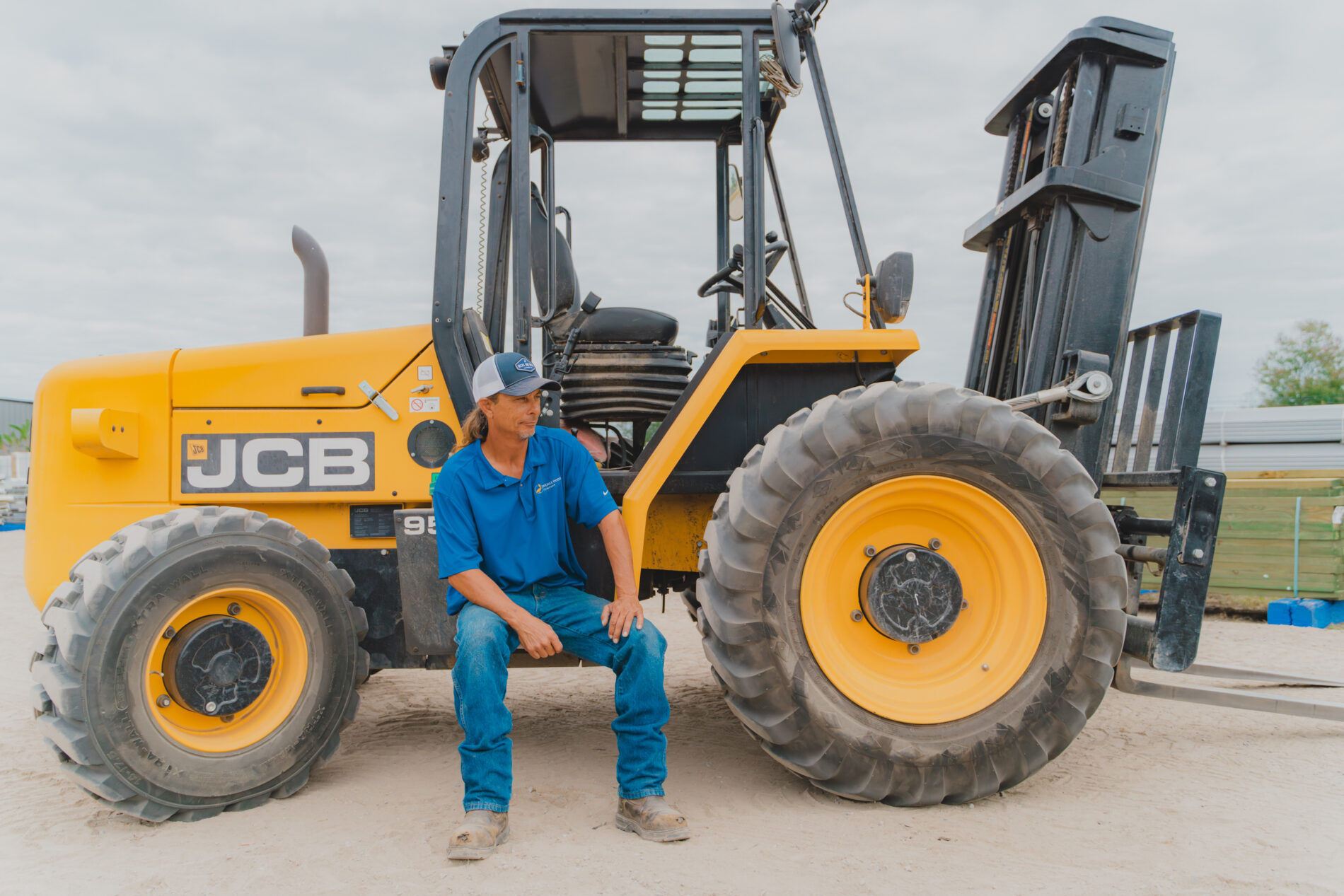 Decks & Docks employee at the Panama City Beach, Florida location sitting on machinery in the lumber yard